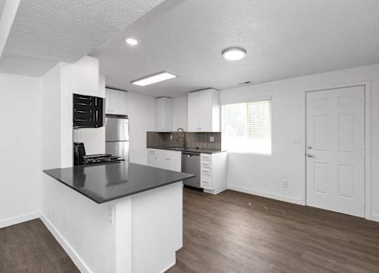 an empty kitchen with white cabinets and a black counter top