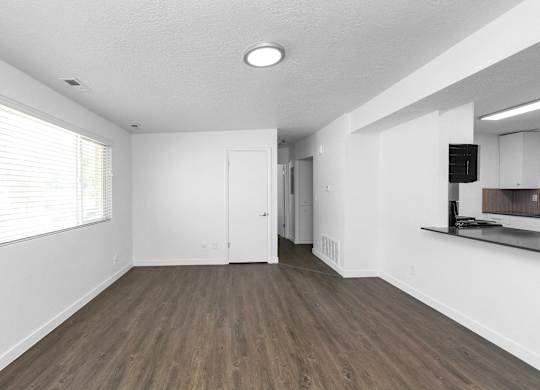 an empty living room with white walls and a window