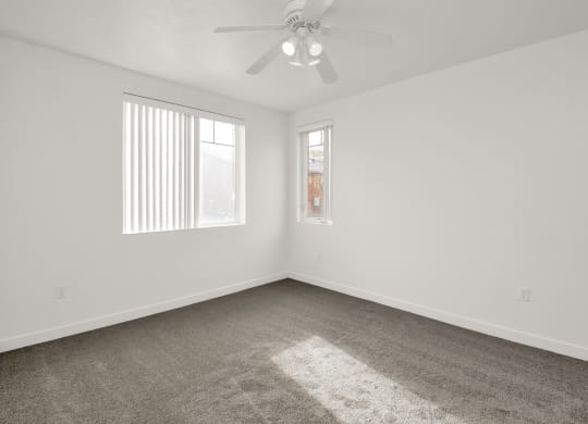 an empty room with carpet and a ceiling fan