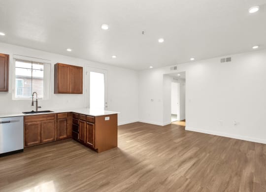 an empty kitchen and living room with wood floors and white walls
