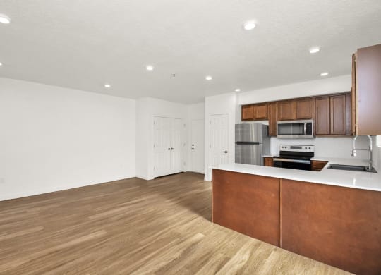 an empty living room and kitchen with wood flooring and white walls