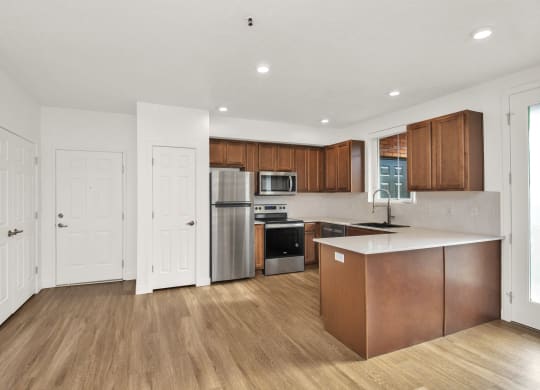 an empty kitchen with wooden floors and white walls and stainless steel appliances