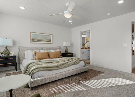 A bedroom with a bed, nightstands, and a ceiling fan.