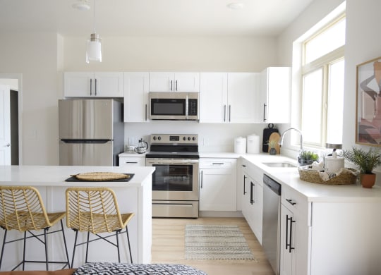 a kitchen with white cabinets and a white island with two stools