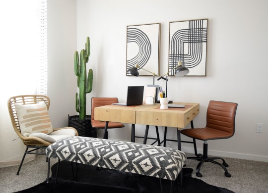a home office with three chairs and a desk with a computer and a cactus