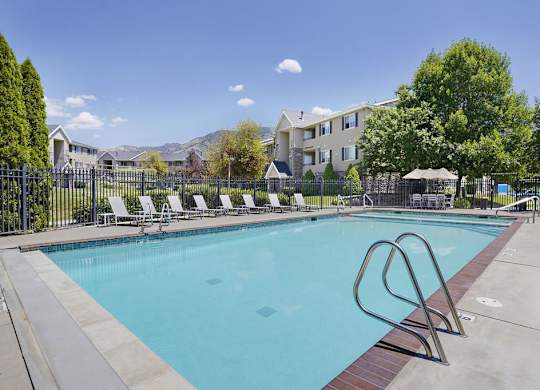 A swimming pool with a diving board in front of a resort.