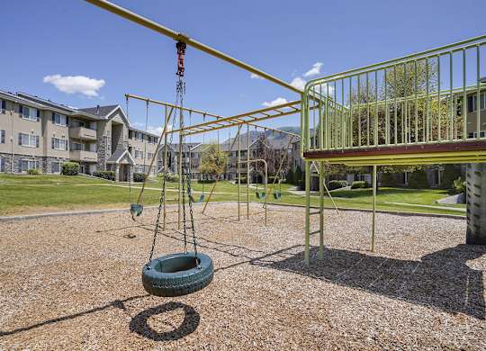 A tire swing hangs from a metal frame in a playground.