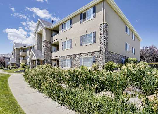Apartment building with a stone facade and a green lawn in front.