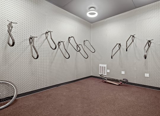 A room with a wall of hooks and a bicycle wheel on the floor.