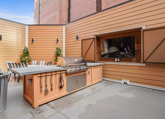 A wooden outdoor kitchen with a grill and sink.