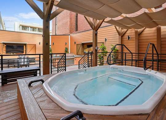 A hot tub on a wooden deck with a canopy over it.