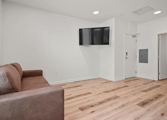 A living room with a brown couch and a flat screen TV mounted on the wall.