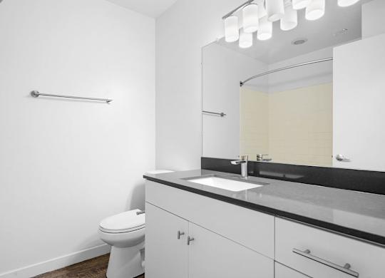 A white bathroom with a toilet, sink, and mirror.