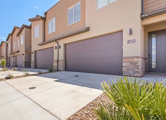 a sidewalk in front of a house with a garage door