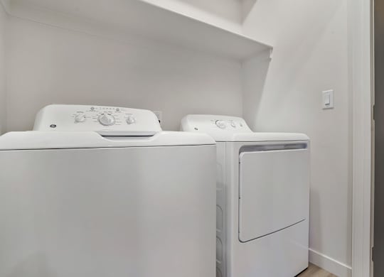 Two white front loading washing machines in a laundry room.