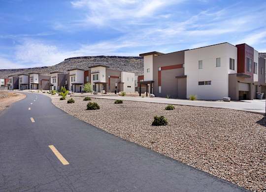 A road with a yellow line in the middle runs through a housing development.