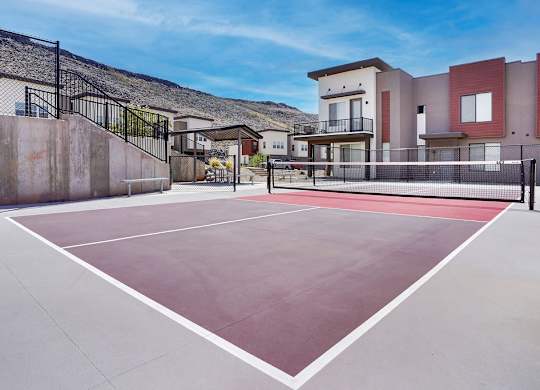Tennis court in front of a building with a black fence.