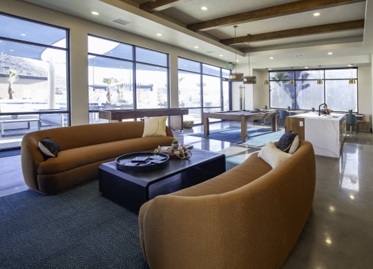 a living room with brown couches and a table and windows