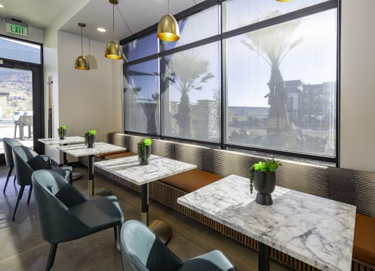 a bistro area with marble tables and chairs and a large window