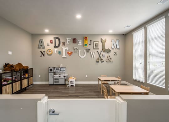a room with two tables and two chairs and a wall with a alphabet sign on the wall