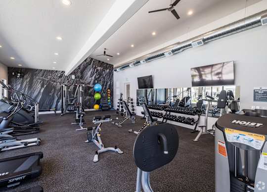 A gym with a variety of equipment including treadmills, weights, and exercise machines.