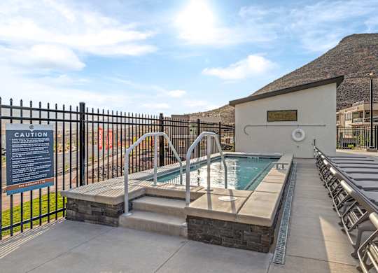 A pool area with a caution sign and a hot tub.