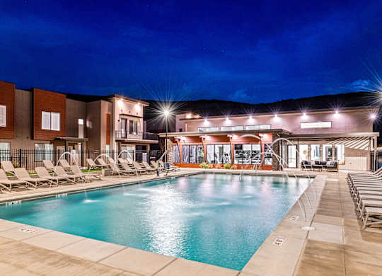 A swimming pool area with lounge chairs and a building in the background.
