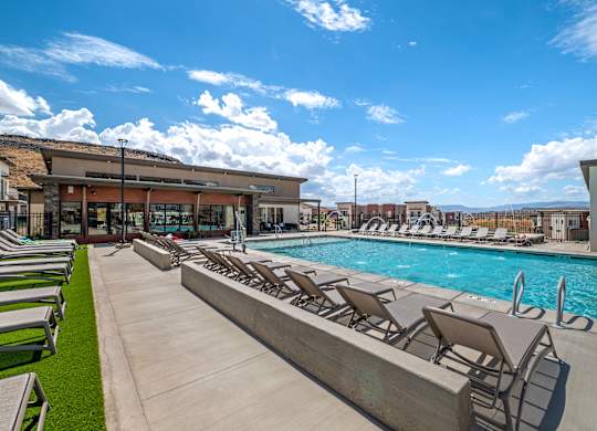A pool with sun loungers and a building in the background.