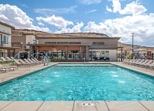 A large swimming pool with lounge chairs and a building in the background.