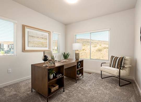 A room with a chair, a desk, and a painting on the wall.