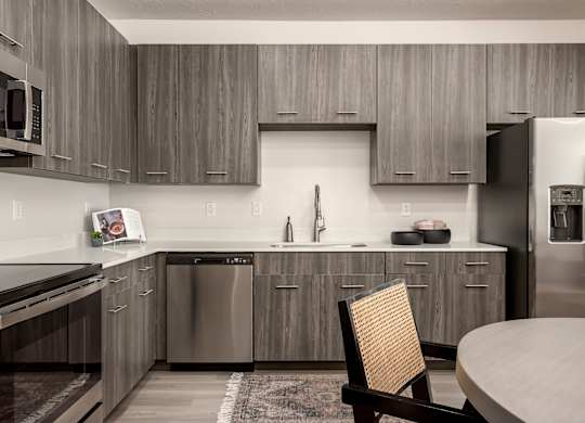 A modern kitchen with a wooden chair and stainless steel appliances.