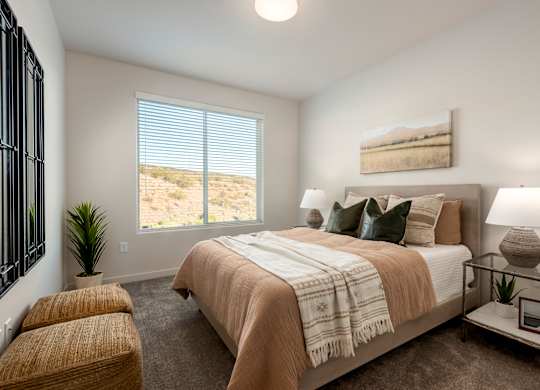 A bedroom with a large bed and a window overlooking a desert landscape.