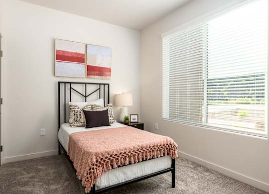 A bedroom with a bed, pillows, a lamp, and a painting on the wall.