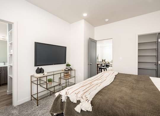 A bedroom with a large bed and a flat screen TV mounted on the wall.