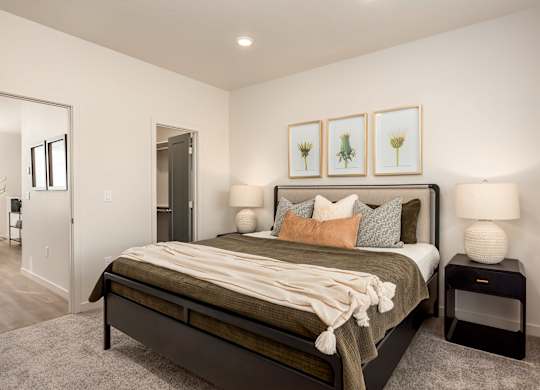 A bedroom with a bed, nightstands, and framed pictures on the wall.
