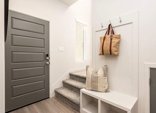 A brown bag hangs on a hook on a white wall.