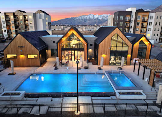 A modern building with a pool in the foreground and snow-capped mountains in the background.