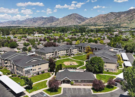 A large building complex with a parking lot in front and mountains in the background.