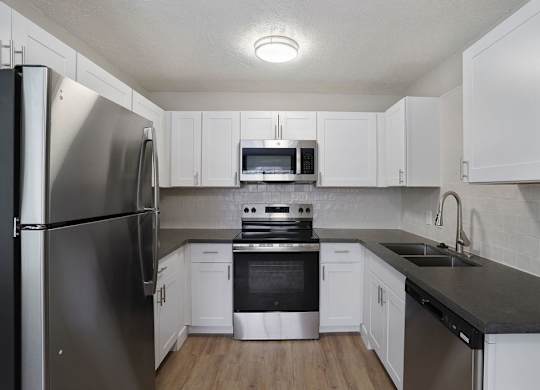 A kitchen with white cabinets and a black countertop.