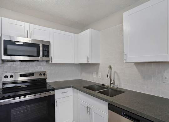 A kitchen with white cabinets and a black stove top oven.