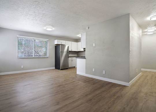 A kitchen area with a refrigerator, cabinets, and a window.