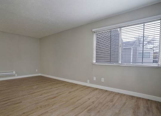 A room with wooden flooring and a window with blinds.