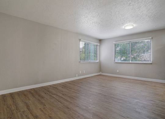 A room with wooden floors and two windows.