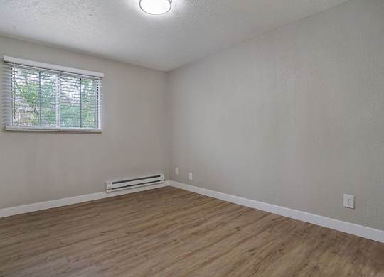 A room with a window and a wooden floor.