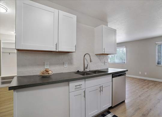 A kitchen with white cabinets and a black countertop.