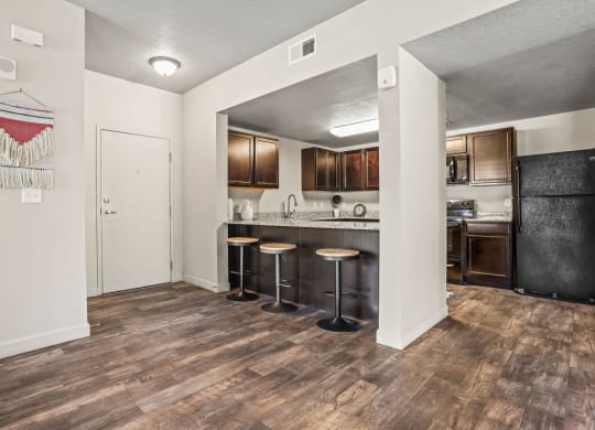 a kitchen with a bar with stools and a refrigerator