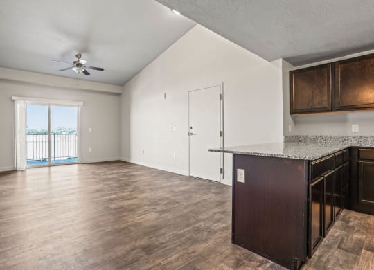 an empty living room and kitchen with a door to a balcony