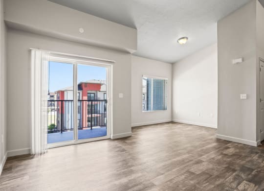 an empty living room with a sliding glass door to a balcony
