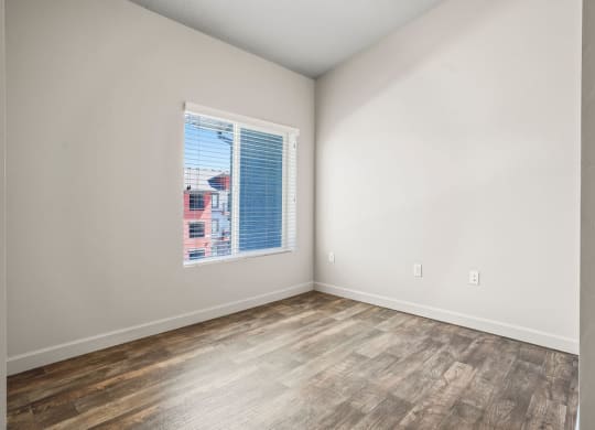 an empty room with a window and wood floors