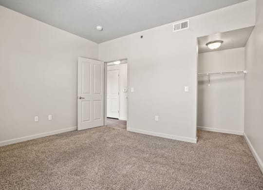 an empty living room with a closet and a door to a hallway